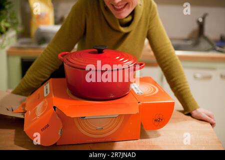 Una donna sorride dopo aver aperto un regalo di un forno olandese le Creuset nella sua cucina casalinga a Seattle, Washington. Foto Stock