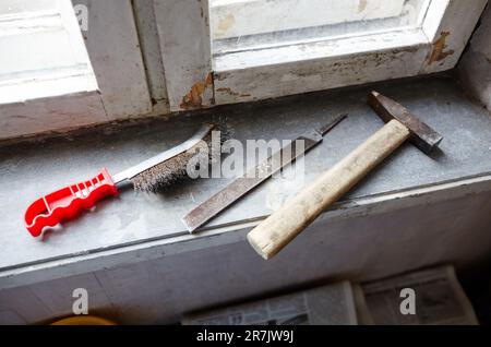 Riparazione del vecchio finestrino danneggiato o smontaggio prima di installare il nuovo primo piano. Riparazione di un telaio di una finestra, utilizzando strumenti per la ristrutturazione di vecchie finestre Foto Stock