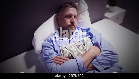 Uomo dorme sul letto con fascio di moneta note Foto Stock