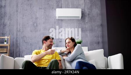Felice Coppia giovane la regolazione della temperatura del condizionatore aria da remoto Foto Stock