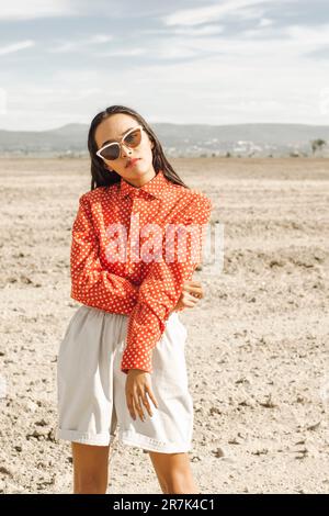 Giovane donna alla moda che indossa occhiali da sole nel deserto Foto Stock