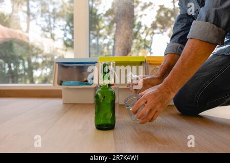 Uomo che smista i rifiuti nel contenitore di separazione dei rifiuti Foto Stock