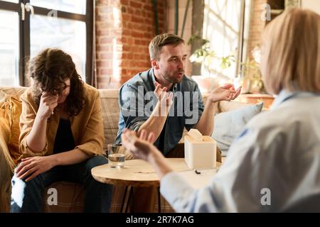 Giovane coppia che discute i loro problemi con lo psicologo durante la sessione psico Foto Stock