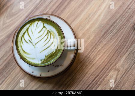 Una tazza di latte match sul tavolo. Arte tardiva su sfondo verde Foto Stock