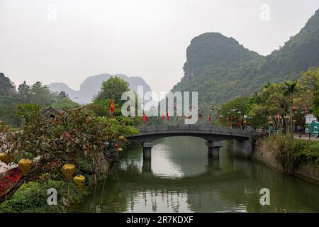 Ninh Binh, Vietnam-Aprile 2023; Vista di un ponte tradizionale che attraversa un fiume che conduce al Delta del Fiume Rosso nel paesaggio di Trang An Foto Stock