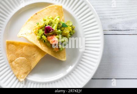 Un piatto con tortillas di mais croccanti sormontato da guacamole fatte in casa. Foto Stock