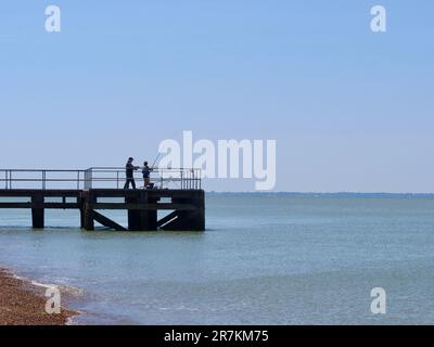 Felixstowe, Suffolk - 16 giugno 2023 : due persone che pescano da un molo nel porto di Harwich. Foto Stock