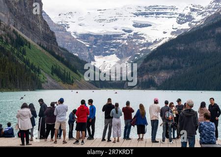 Lago Louise, AB, Canada-Agosto 2022; Visualizza molti turisti sul lungomare delle acque alimentate dal ghiacciaio del lago Louise con molte canoe sul lago contro la b Foto Stock