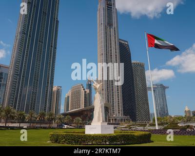 20 marzo 2023, Dubai, Emirati Arabi Uniti: Statua a tre dita vicino alla bandiera degli Emirati Arabi Uniti nei giorni di sole e Burj Khalifa, conosciuto come il grattacielo più alto del mondo. E' conosciuto per essere l'edificio piu' alto del mondo. Foto Stock