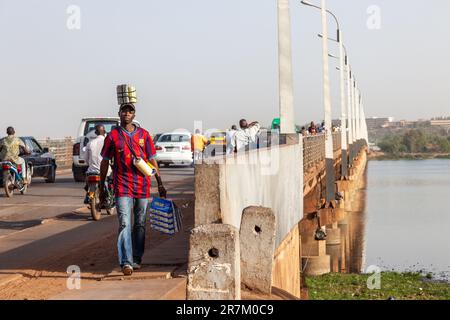 Uomo che trasporta vari oggetti alla fine dell'attraversamento del fiume Niger presso il Pont des Martyrs a Bamako, Mali. Foto Stock