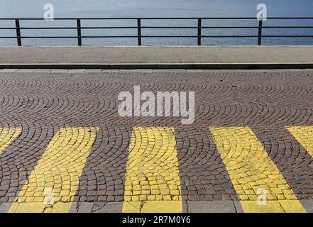 Attraversamento pedonale su strada acciottolata e marciapiede lungo il lungomare, Como, Italia Foto Stock