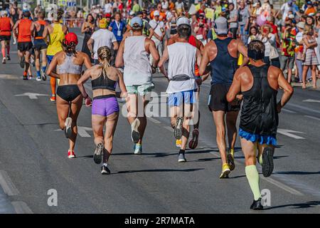 la vista posteriore dei corridori di gruppo atleti donne e uomini che corrono la maratona della città, i tifosi della strada guardano gli atleti Foto Stock