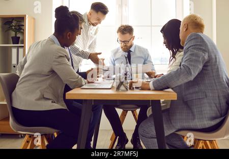 Gruppo di persone in viaggio d'affari che lavorano e comunicano mentre si è seduti alla scrivania dell'ufficio Foto Stock