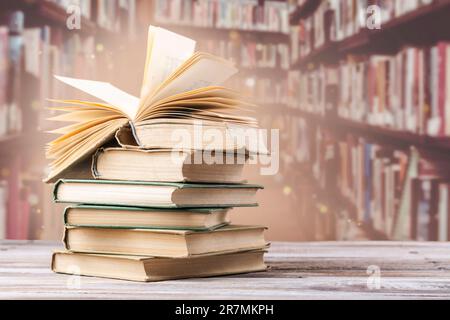 Prenota con pagine aperte e libri impilati sulla scrivania di lettura della biblioteca. Biblioteca nazionale, libri amanti giorno o mese. Ritorno alla scuola o all'istruzione Foto Stock