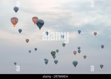 Un'immagine di più palloncini ad aria calda che volano su un cielo nuvoloso in Cappadocia. Foto Stock