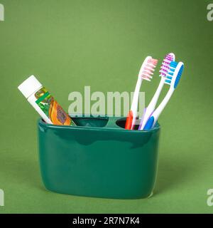 Un set di tre spazzolini multicolore, un tubo di dentifricio ecologico Foto Stock