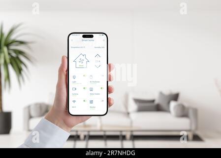 Concetto di app Smart Home sulla casa mobile in mano alla donna. Soggiorno interno in background Foto Stock