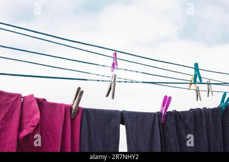 Sulla linea di lavaggio è appesa una spilla. Una corda con biancheria pulita e vestiti all'aperto il giorno della lavanderia. Sullo sfondo della natura verde Foto Stock