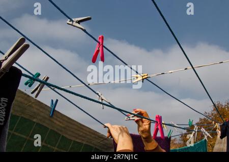 Sulla linea di lavaggio è appesa una spilla. Una corda con biancheria pulita e vestiti all'aperto il giorno della lavanderia. Sullo sfondo della natura verde Foto Stock