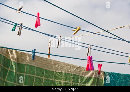 Sulla linea di lavaggio è appesa una spilla. Una corda con biancheria pulita e vestiti all'aperto il giorno della lavanderia. Sullo sfondo della natura verde Foto Stock