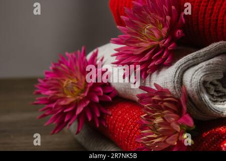 Modello di maglia colorata maglioni closeup. Prodotto in lana merino fatto a mano. Una pila di vestiti piegati con fiori Foto Stock