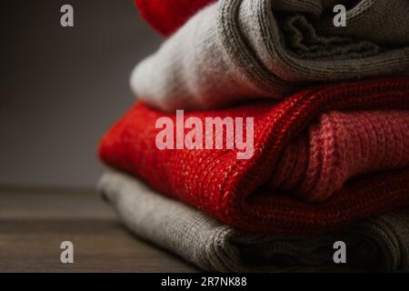 Modello di maglia colorata maglioni closeup. Prodotto in lana merino fatto a mano. Una pila di vestiti piegati con fiori Foto Stock