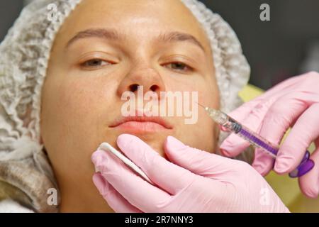 plastica contorno. Un cosmetologo inietta una tossina botulinica per stringere e levigare le rughe sulla pelle di una faccia femminile Foto Stock