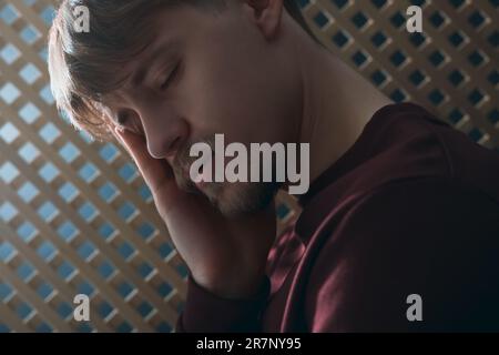 Rovesciato giovane uomo durante la confessione in cabina, primo piano Foto Stock