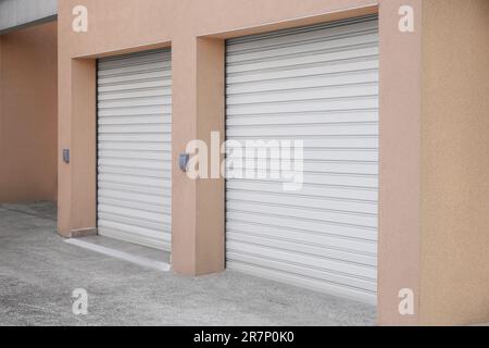 Edificio con porte da garage con serranda a rullo bianca Foto Stock