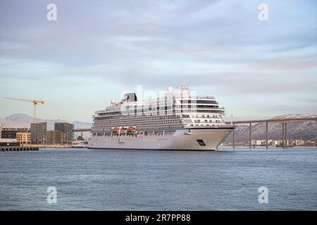 Una maestosa nave da crociera vichinga Venere ormeggiata nel porto di Tromso, contro le montagne innevate Foto Stock