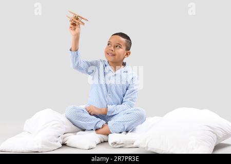 Ragazzino afroamericano con piano in legno e morbida coperta su sfondo chiaro Foto Stock