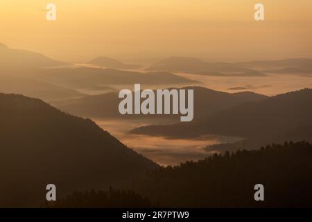 Strati delle colline durante la nebbia mattutina sulle montagne di Bijele stijene, Croazia Foto Stock