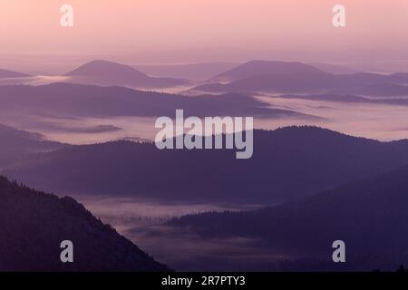 Strati delle colline durante la nebbia mattutina sulle montagne di Bijele stijene, Croazia Foto Stock