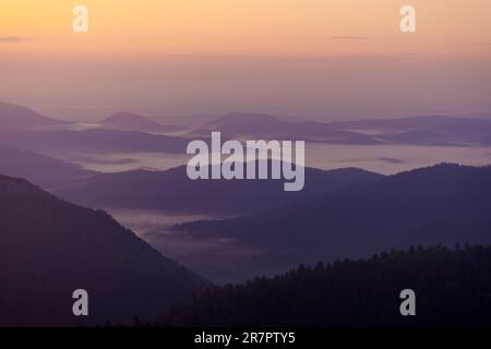 Strati delle colline durante la nebbia mattutina sulle montagne di Bijele stijene, Croazia Foto Stock