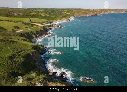 Vista aerea dell'aspra costa sud della Cornovaglia vicino al villaggio di Kuggar con l'oceano limpido che si infrange sulle rocce. Foto Stock