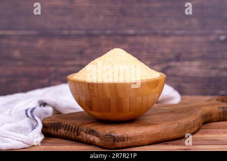 Farina di semola biologica secca su fondo di legno. Semola biologica cruda in ciotola di legno Foto Stock