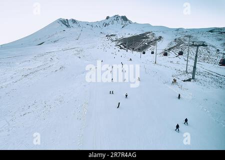 Sciatori sulle piste innevate della stazione sciistica in serata. Vista aerea. Monte Erciyes, provincia di Kayseri, Turchia Foto Stock