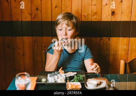 I bambini mangiano i panini di Sushi a casa. Buon ragazzo pronto a mangiare  sushi Foto stock - Alamy