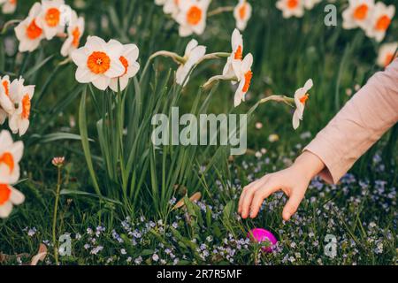 Bambina che raccoglie uova colorate nel parco. Concetto di caccia pasquale Foto Stock