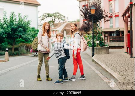 Gruppo di 3 bambini divertenti con zaini, 2 scolaresche e un preschooler, concetto di ritorno a scuola Foto Stock