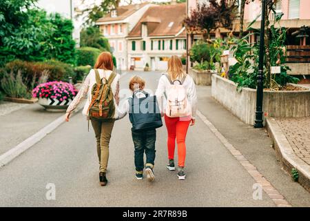 Gruppo di 3 bambini divertenti con zaini, 2 scolaresche e un preschooler, concetto di ritorno a scuola Foto Stock