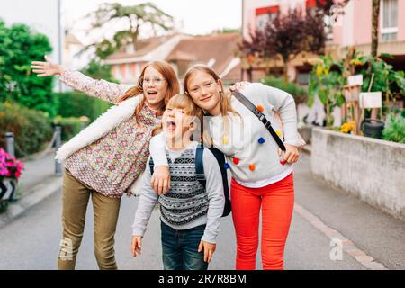 Gruppo di 3 bambini divertenti con zaini, 2 scolaresche e un preschooler, concetto di ritorno a scuola Foto Stock