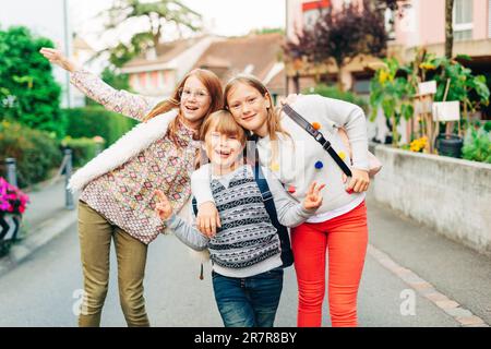 Gruppo di 3 bambini divertenti con zaini, 2 scolaresche e un preschooler, concetto di ritorno a scuola Foto Stock