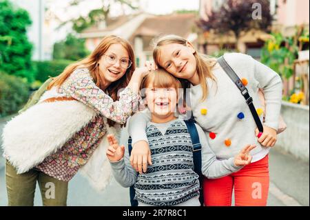 Gruppo di 3 bambini divertenti con zaini, 2 scolaresche e un preschooler, concetto di ritorno a scuola Foto Stock