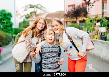 Gruppo di 3 bambini divertenti con zaini, 2 scolaresche e un preschooler, concetto di ritorno a scuola Foto Stock