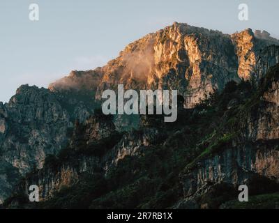 Montagna illuminata dall'alba: Il sole che sorge illumina la montagna, emettendo una tonalità dorata che aggiunge un tocco di magia al paesaggio mozzafiato. Foto Stock