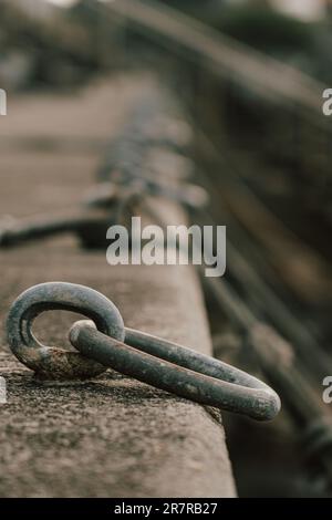 Un robusto anello metallico incorporato in pietra è pronto a mettere al sicuro le barche, incarnando l'essenza dei legami marittimi e dell'esplorazione nautica. Foto Stock