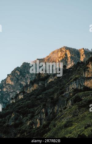 Montagna illuminata dall'alba: Il sole che sorge illumina la montagna, emettendo una tonalità dorata che aggiunge un tocco di magia al paesaggio mozzafiato. Foto Stock