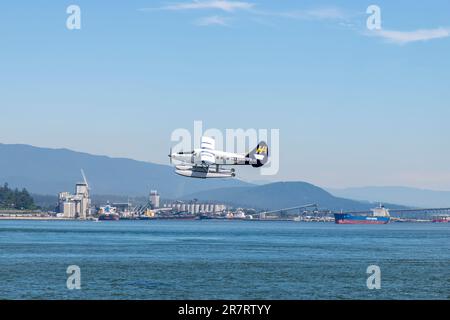 Vancouver, BC, Canada-Luglio 2022; Vista ravvicinata di un idrovolante o di un idrovolante appena sopra l'acqua del porto di Vancouver con l'area industriale di North Shore Foto Stock