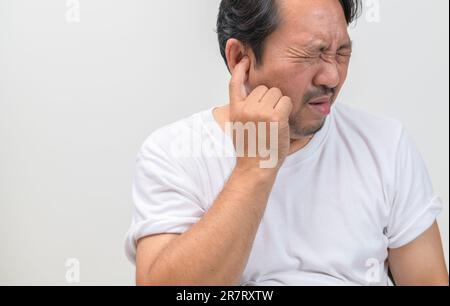 L'uomo bearded ha un'orecchio pruriginoso o un dolore nel suo orecchio isolato su sfondo bianco. Concetto di assistenza sanitaria. Foto Stock